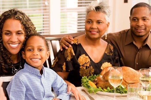 Black family sitting for dinner in a private dinning room of a Fellowship Square community.